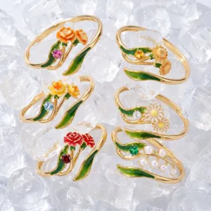 Detailed close-up of exquisite gold-plated enamel flower rings set on ice background.