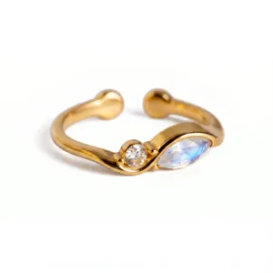 Primer plano detallado de un elegante anillo abierto dorado con diseño de doble piedra de cristal.