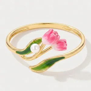 Close-up detail of gold-plated open ring featuring pink enamel tulips and white pearl accent.