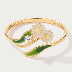 Close-up of gold-plated daisy ring featuring enamel flowers, green leaves and sparkling CZ stone.