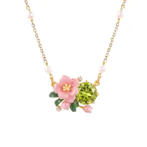 Close up of exquisite gold plated necklace featuring pink enamel flower and green crystal.