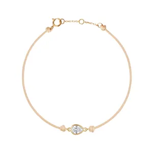 Bracelet minimaliste avec zircone cubique en forme de poire et cordon beige, plaqué or 18k.