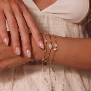 Detailopname van delicate vergulde armbanden met sprankelende zirkoniastenen om de pols.