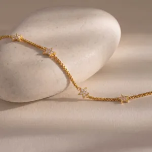 Goudkleurige roestvrijstalen schakelarmband met sprankelende zirkonia sterren detailopname.