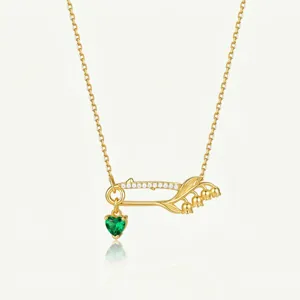 Collier épingle de sûreté doré avec cristal cœur vert et pendentif muguet élégant.