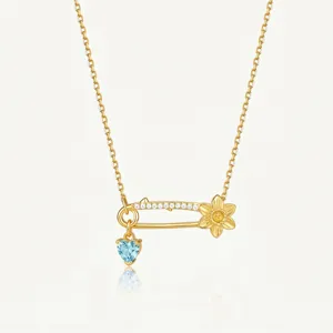 Gros plan détaillé du élégant collier pendentif épingle de sûreté doré cristal cœur.