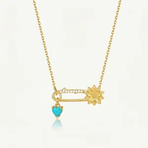 Collier épingle de sûreté plaqué or avec pavé de cristaux, motif floral et pendentif cœur.