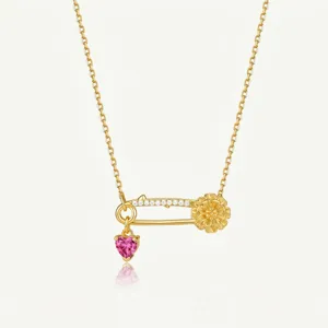 Magnifique collier épingle de sûreté doré avec pendentif cœur rose et fleur délicate.