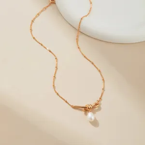 Gedetailleerd overzicht van vergulde ketting met kleine kraaltjes en elegante strik parel hanger.