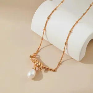 Chique vergulde parelketting met een elegante strikhanger en fijne kettingdetails.
