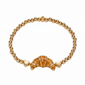 Bracelet de perles extensible doré avec charm croissant émaillé et détails de petits cœurs.