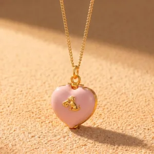 Vue détaillée d'un joli collier chaîne or avec médaillon cœur rose et pendentif chiot.