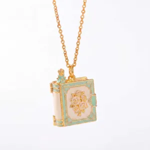 Gedetailleerd opname van vergulde sprookjesboek medaillon ketting met mint emaille en roos.