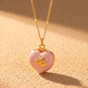 Collier chaîne doré avec médaillon cœur rose et détail de renard doré en gros plan.