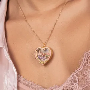 Detailopname van de hartvormige medaillonketting met doorzichtig venster en miniatuurhangers.