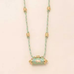 Detailed shot of turquoise braided cord necklace featuring prayer wheel bull pendant and gold beads.
