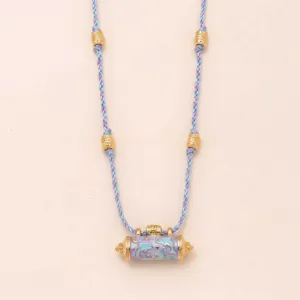 Detailed shot of the gold-plated dolphin cylinder pendant and purple braided rope.