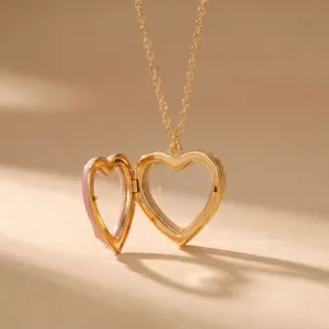 Gouden hartje medaillon hanger ketting openend, transparant hol design met roze emaille detail.