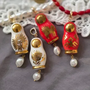 Collier pendentif poupée russe vintage avec motifs dorés de fleurs et de chevaux.