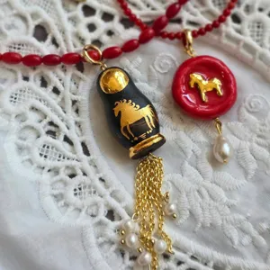 Vue détaillée d'un collier pendentif cheval poupée russe vintage avec perles et perles rouges.