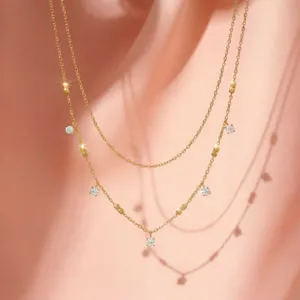 Prachtige dubbellaagse goudkleurige ketting met fijne vierkante kralen en sprankelende hangers.