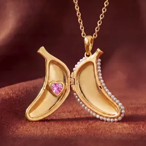 Exquisite gold banana locket necklace featuring a pink heart crystal and elegant pearl edging.