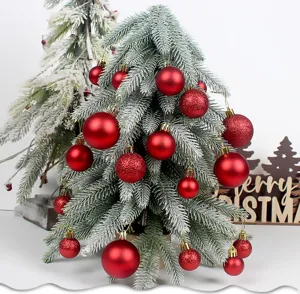 Detailed closeup of tabletop frosted Christmas tree decorated with assorted red bauble ornaments.