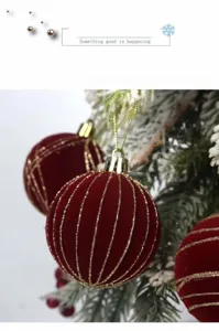 Λεπτομέρεια κόκκινης βελούδινης χριστουγεννιάτικης μπάλας με χρυσές γραμμές σε κλαδί.