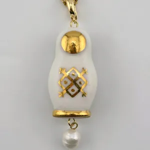 Gros-plan détaillé du pendentif poupée russe vintage en céramique blanche et perle.