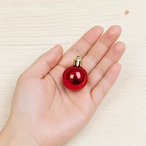 Close-up of a small red shiny Christmas tree bauble held on hand, showing size for holiday decor.