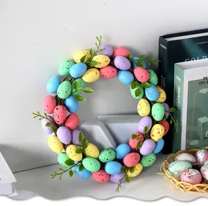 Detail shot of colorful Easter egg wreath with speckles and green leaves for home decor.