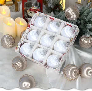 Vista detallada de bolas navideñas blancas y champán en una caja de regalo festiva.