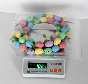 Easter egg wreath detail shot showing colorful speckled eggs and green leaves on scale.