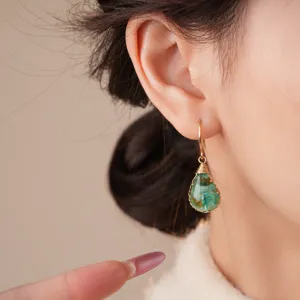 Close-up detail view of bohemian resin flower teardrop dangle earrings worn on ear model.