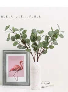 Detailed view of artificial eucalyptus leaves greenery branches placed in a elegant white vase.