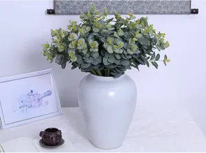 Artificial eucalyptus branch detail view, green money leaf plant arrangement inside a ceramic vase.