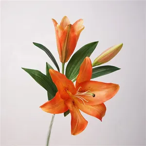 Detailed close-up of artificial orange lily flower with realistic petals and green leaves.