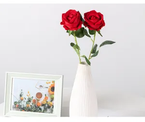 Vue détaillée de roses rouges artificielles en vase céramique blanche avec cadre.