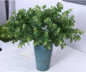 Artificial eucalyptus plant detail, green money leaves in blue ceramic vase, indoor decor close up.