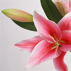 Close-up detail of artificial pink lily flower with green leaves and bud, home decor.
