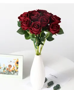 Bouquet de roses rouges artificielles dans un vase en céramique blanche pour déco de mariage détail.
