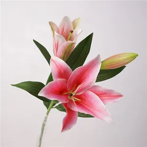 Close-up detail of artificial pink lily flower with green leaves and realistic petal texture.