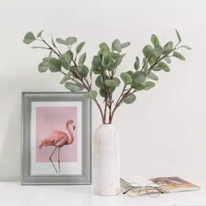 Artificial eucalyptus branches with textured vase for home decor, elegant green plant setup.