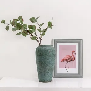 Artificial eucalyptus leaves branches in rustic ceramic vase for modern home decor setup.