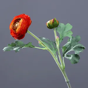 Artificial peony flower detail shot, vibrant red-orange blossom and green leaves for home decor.