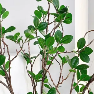Close-up of artificial green plant branch with realistic leaves and brown stem for decor.