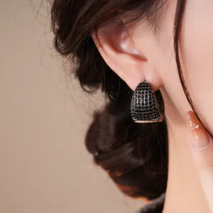 Primo piano di eleganti orecchini a cerchio goccia con zirconi neri moda femminile chic