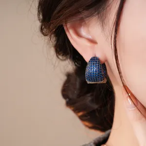 Dettaglio di orecchini a cerchio pavé in zircone blu, gioiello geometrico elegante da donna.