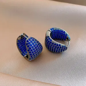 Primo piano dettagliato di orecchini a cerchio spessi con pavè di zirconi blu, stile lusso.