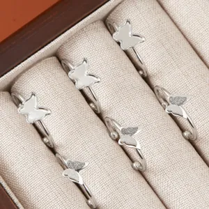 Gros plan de bagues papillon en acier inoxydable rangees proprement dans une boite beige.